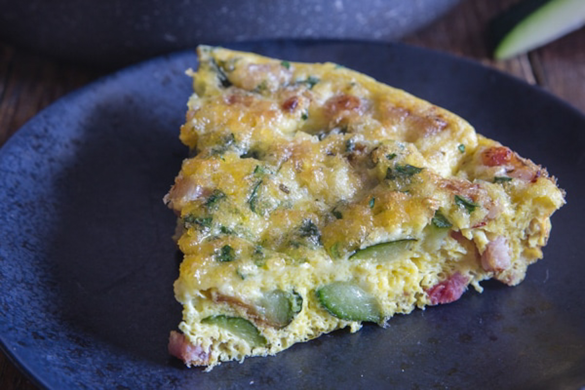 A slice of a baked frittata on a black plate.