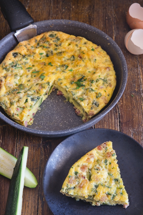 baked frittata in a black pan and a slice on a black plate