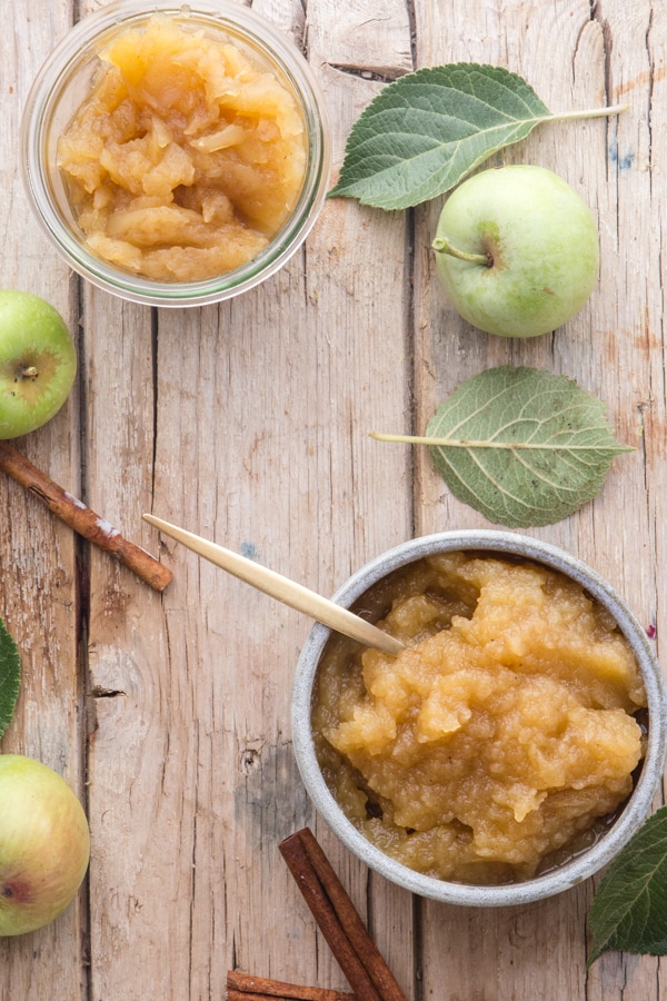 homemade applesauce in a grey bowl and in a glass jar on a wooden board