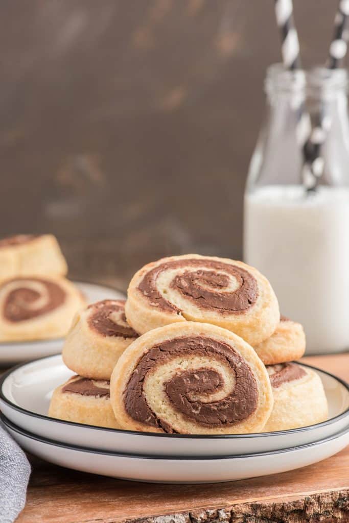 Nutella pinwheel cookies on a white plate. with milk in a jar.