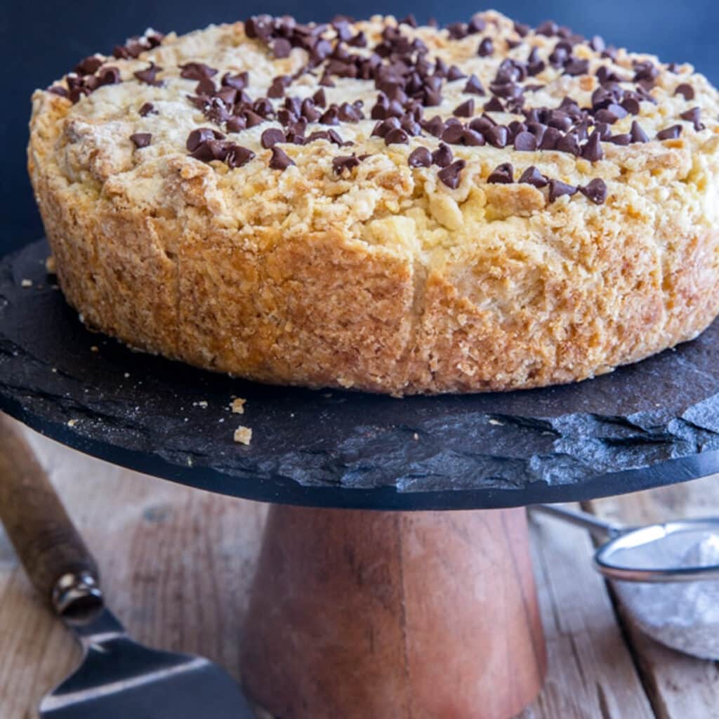 Ricotta crumb cake on a black cake stand.