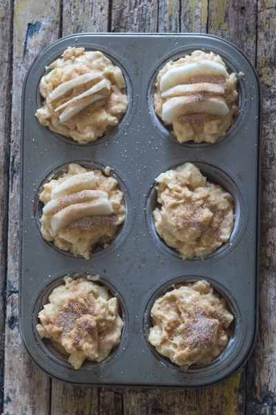 apple muffin ingredients in a 6 muffin tin ready for baking