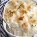 cauliflower casserole in a white baking dish with fresh thyme on top