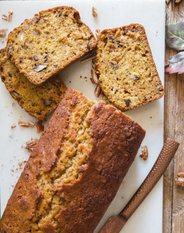 pumpkin bread with 3 slices on a marble cutting board and knife
