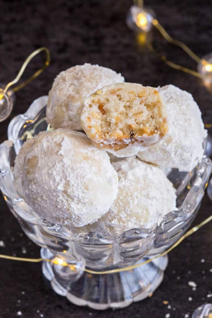 Snowball cookies in a bowl with one cut in half.