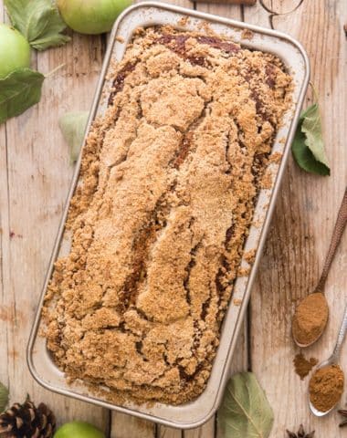 Applesauce bread on a wooden board with apples and spices.