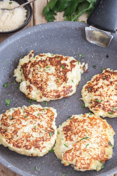 cooked cauliflower fritters in a frying pan browned on both sides