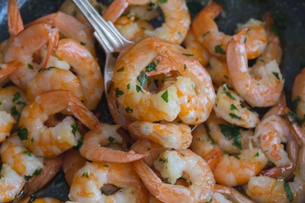 up close sauteed shrimp on a silver spoon