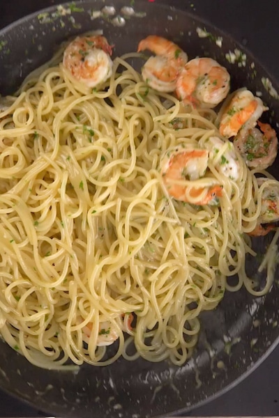 tossing the pasta with the shrimp.