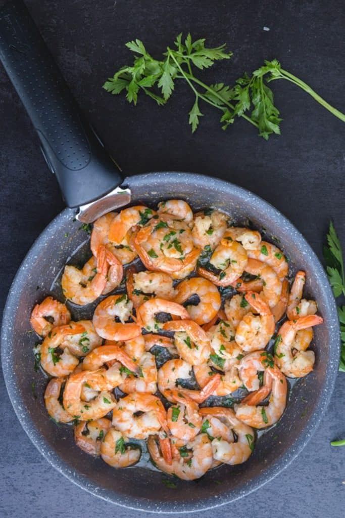 Sauteed shrimp in a black pan.