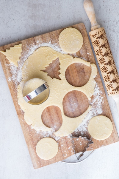 cutting out the cookie dough with cookie cutters on a wooden board