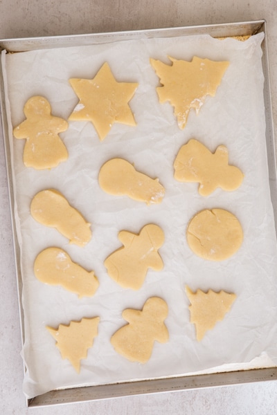 cut out sugar cookies on a parchment paper cookie sheet ready for baking