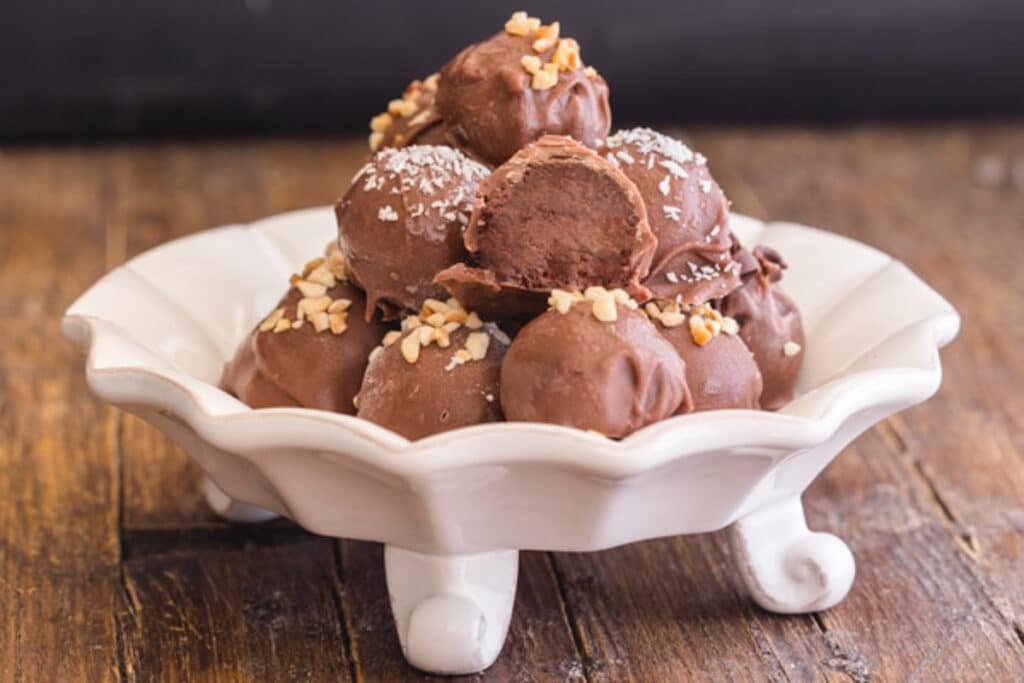 Chocolate candies in a white dish with one cut in half.