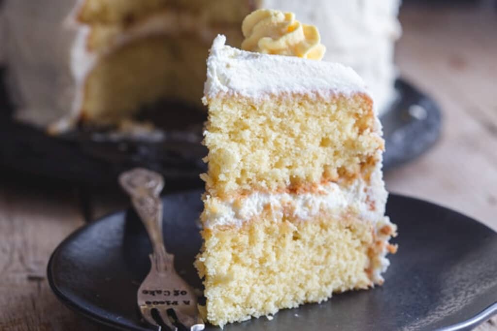 A slice of cake on a black plate.