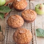 applesauce muffins on a wooden board with applesauce in a container and apples
