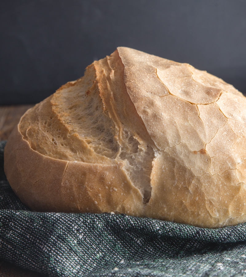 fresh baked bread on a wooden board with a blue cloth