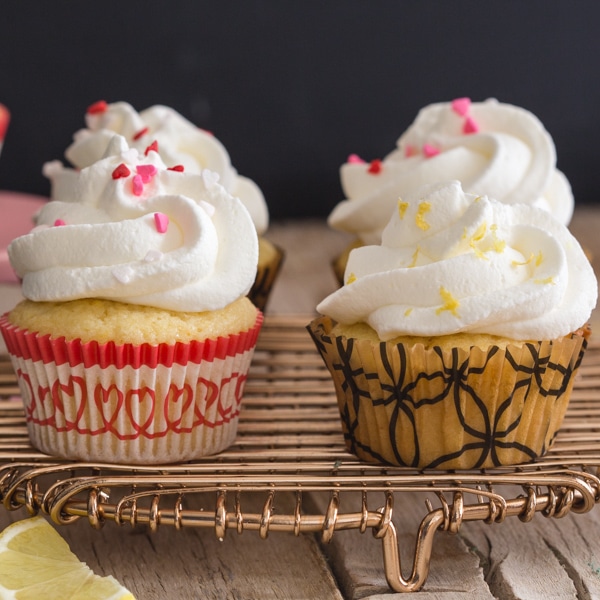 lemon cupcakes on a gold wire rack with one on a small cake stand
