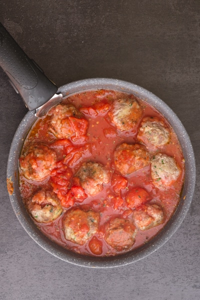 cooking the meatballs in a tomato sauce