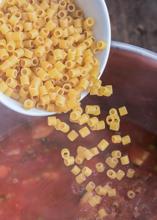 Adding pasta to the pot.