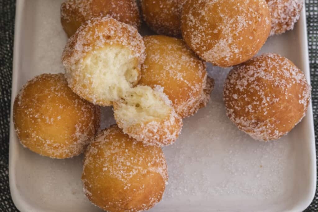 Donut holes on a white plate with one cut in half.