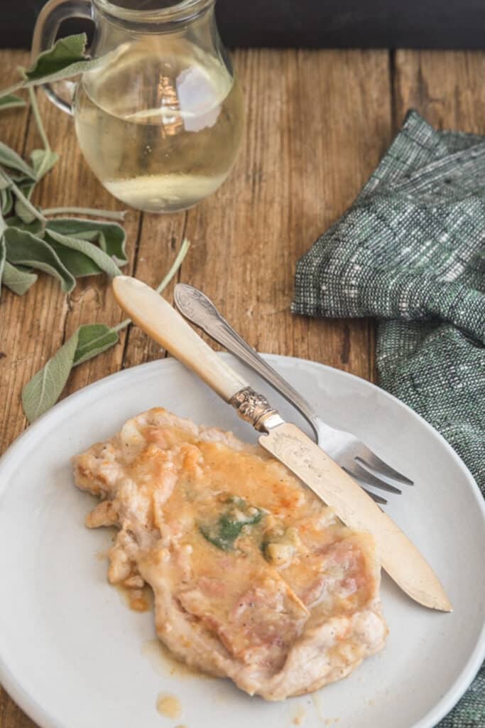 Saltimbocca on a white plate with a knife and fork.