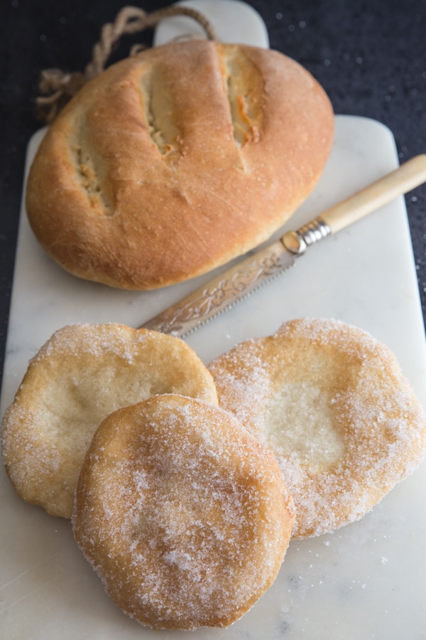 bread and frittelle on a white board with a knife