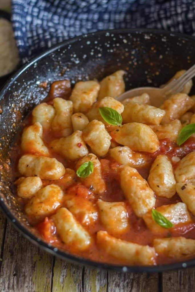 Gnocchi in a tomato sauce in a black pan.