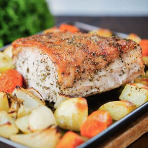 The pork roast and roasted vegetables on the baking sheet.