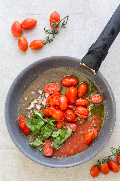 tomatoes, spices and puree in a black pan