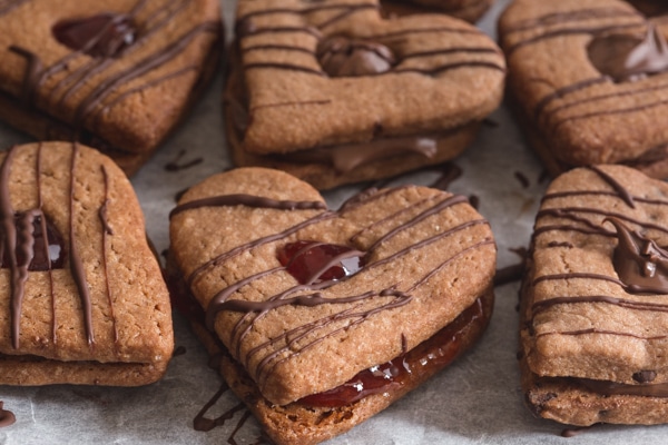 valentine sandwich cookies drizzled with chocolate on a parchment paper