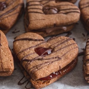 valentine sandwich cookies drizzled with chocolate on a parchment paper