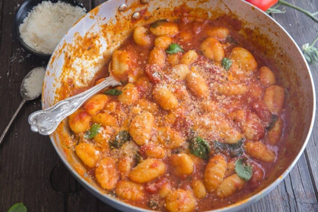 Sauce and gnocchi in a silver pan.