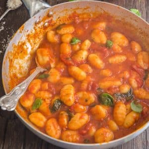 Tomato sauce and gnocchi in a silver pan.