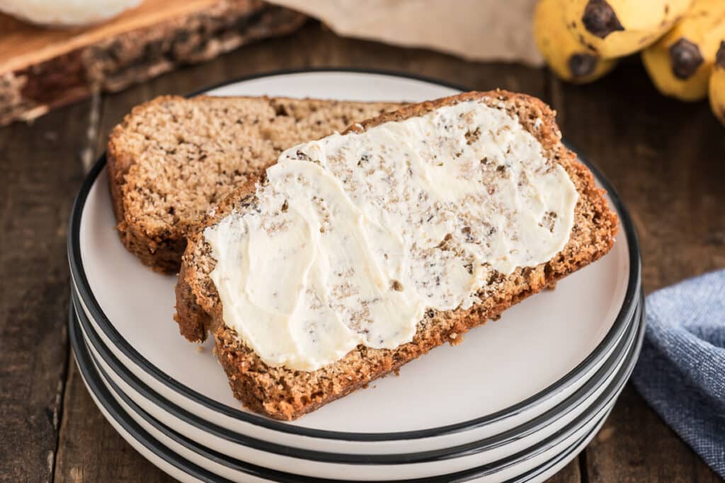 Two slices of banana bread with butter on one slice.