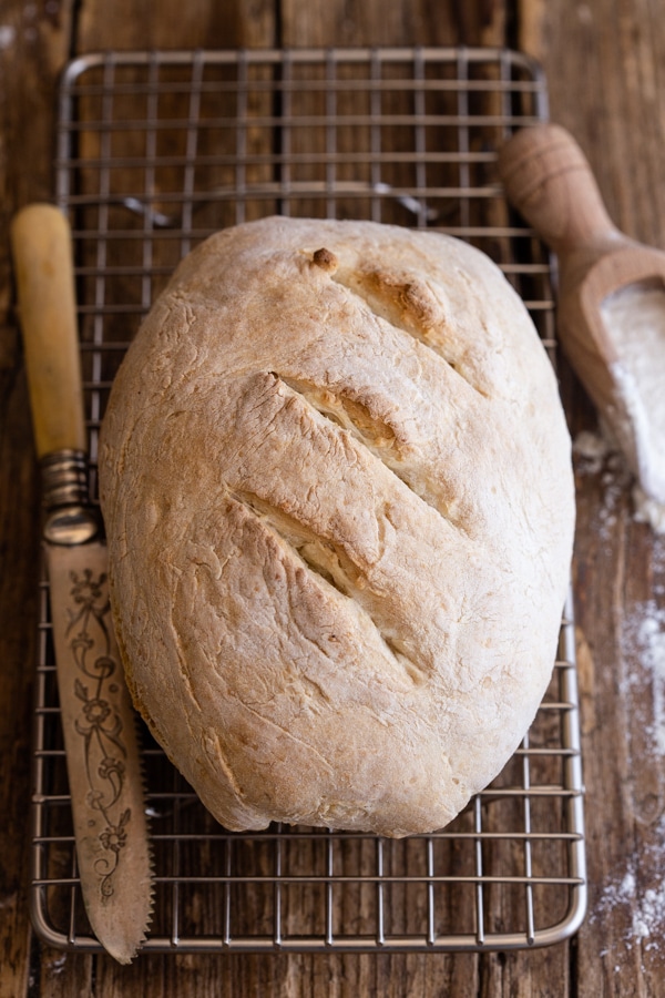 loaf of bread on a wire rack with a knife