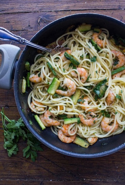 Zucchini and shrimp pasta in a black pan.