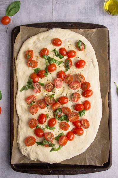 topping the dough with sliced tomatoes