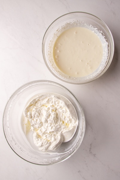 stiff peaked whipped cream in a glass bowl and sweetened condensed milk & ricotta beaten in a glass bowl
