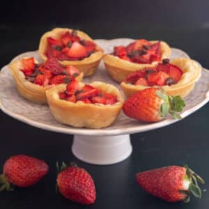 Strawberry tarts on a white plate with 3 strawberries.