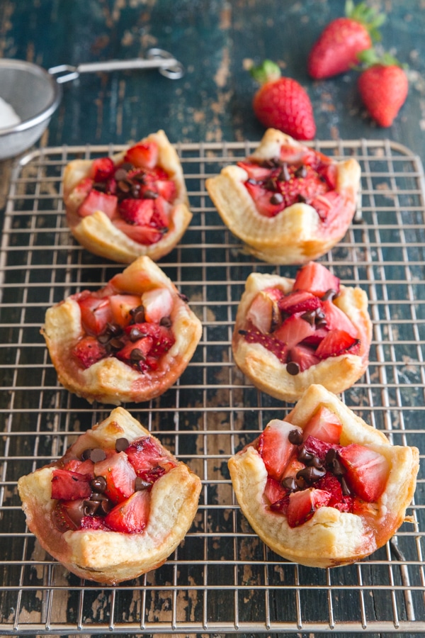 strawberry tarts on a wire rack with 3 fresh strawberries and powdered sugar 