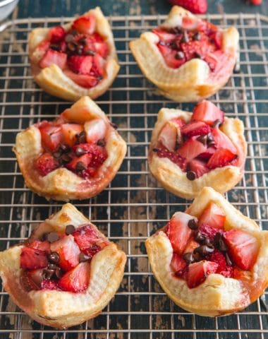 strawberry tarts on a wire rack with 3 fresh strawberries and powdered sugar