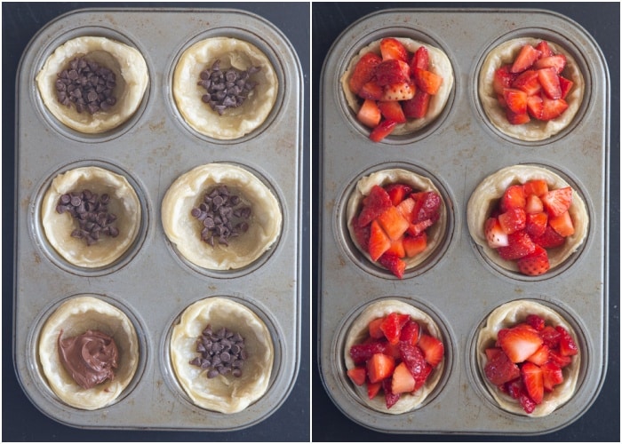 Some chocolate chips in a the tarts with strawberries on top before baking.