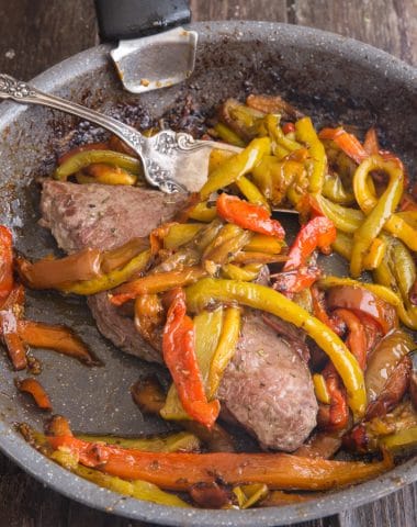 peppers and a steak in a frying pan with a fork