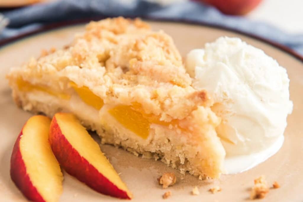 A slice of crumb cake on a plate with a scoop of ice cream.