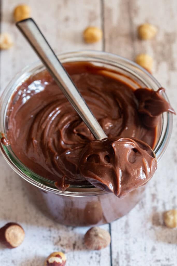 Nutella in a jar and some on a spoon.