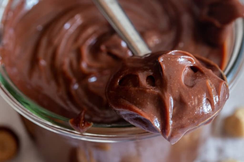 Nutella in a jar and some on a spoon.
