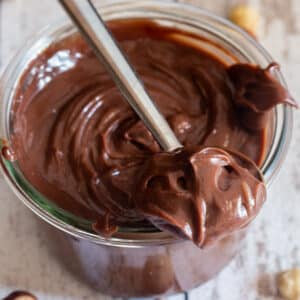 Nutella in a jar and some on a spoon.