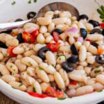 Bean salad in a white bowl with a spoon.