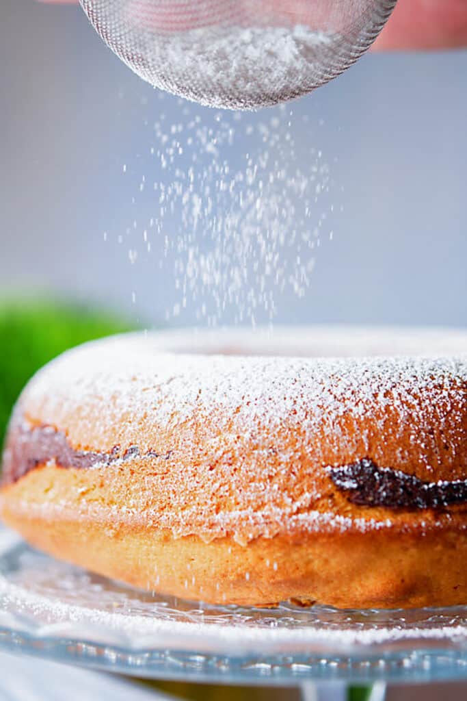 Dusting powdered sugar on the cake.