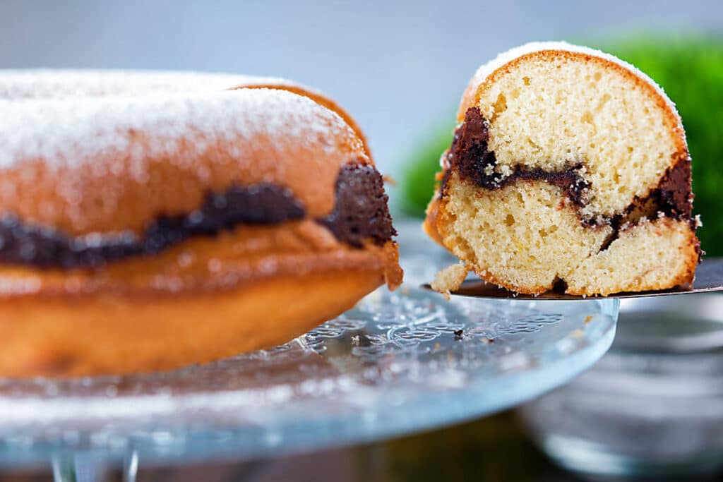 Cake on plate with a slice on a spatula.